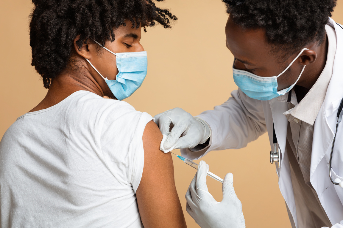 Doctor in Medical Mask Making Vaccine Shot Injection to Black Male Patient